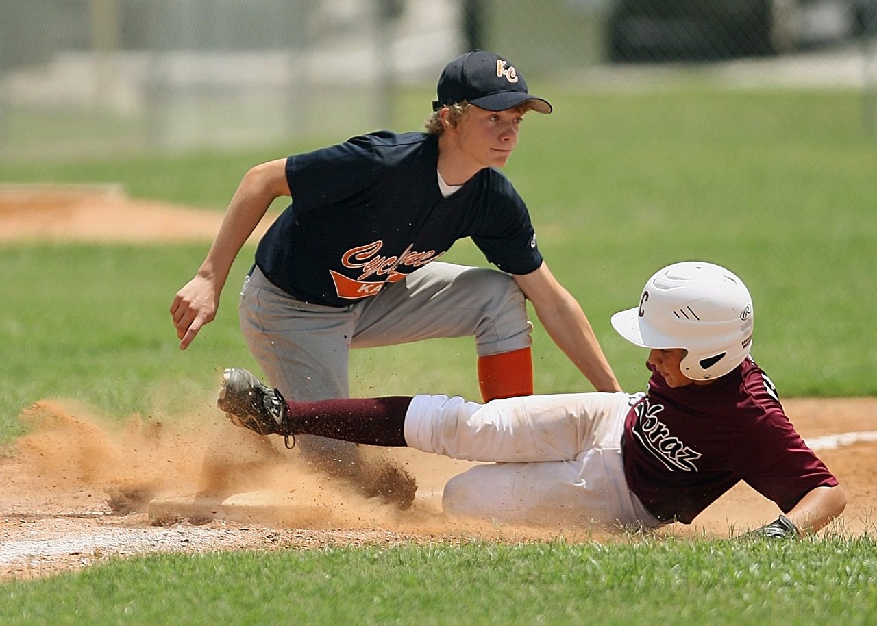 A baseball player sliding into the base while another player tries to tag him out.